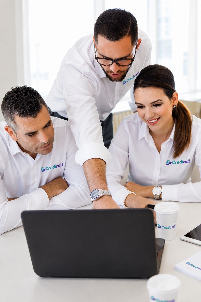 Three Crediroll team members reviewing work on a laptop